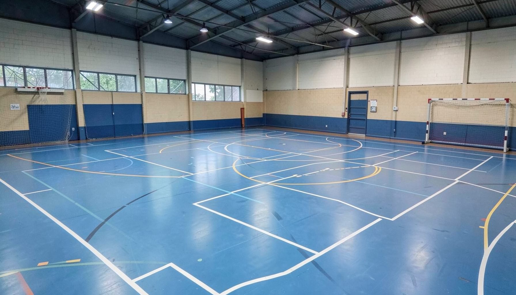 Cancha de futsal cubierta con líneas blancas marcadas, iluminación artificial y ambiente de entrenamiento